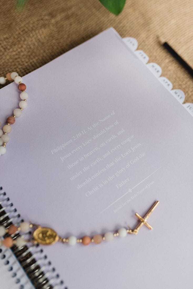 A lilac monthly reflection page with a rosary laid across it