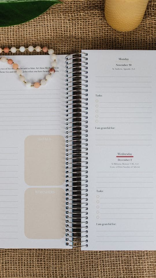 The planner open on a table beside a beeswax candle
